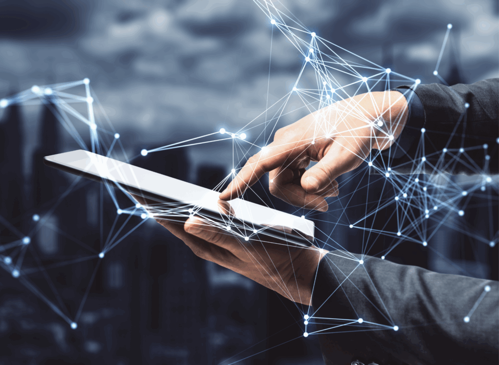 En persons händer håller i en digital surfplatta, med glödande nätverkslinjer och anslutningsnoder överlagrade för att symbolisera efterfrågeacceleration och digital uppkoppling. En stadsbild är suddig i bakgrunden.